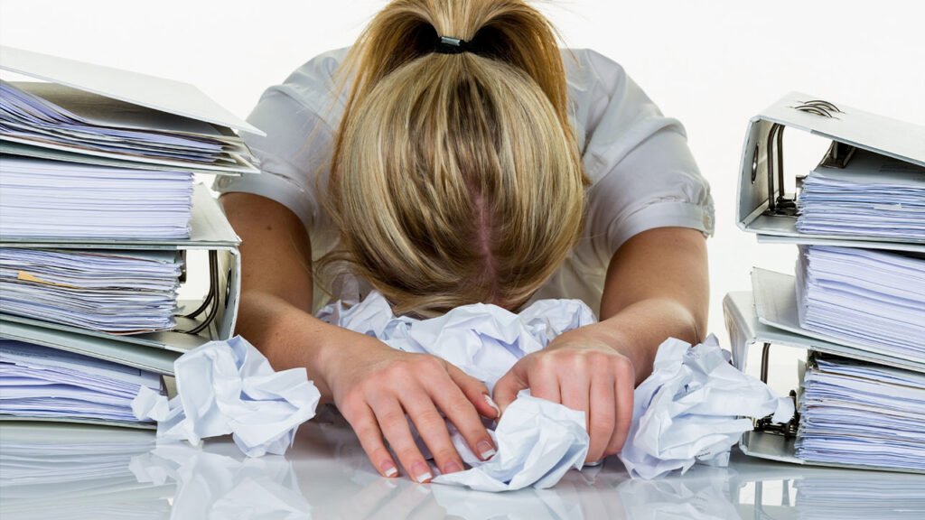 Business owner experiencing content writing burnout A Burned Out Woman Writer Business Owner surrounded by scrunched up paper content