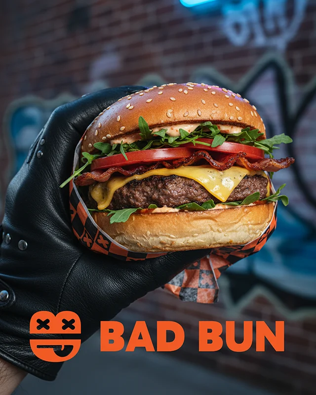 Bad Bun Gourmet Burger Brand Logo with photo of leather-gloved hand holding a tasty burger wrapped in branded wrap